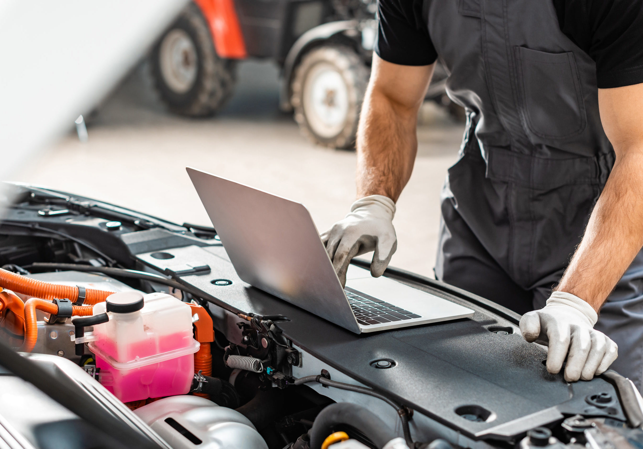 cropped view of mechanic using laptop near car engine compartment